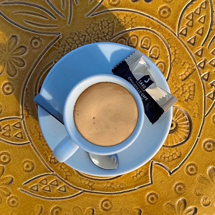 Un café et sa croustille posés sur une mosaïque jaune de Julien Capron